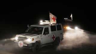 A white four-wheel drive with a red cross on its side and a flag driving in the night