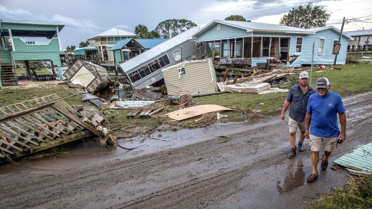 People walk by houses destroyed by a hurricane.