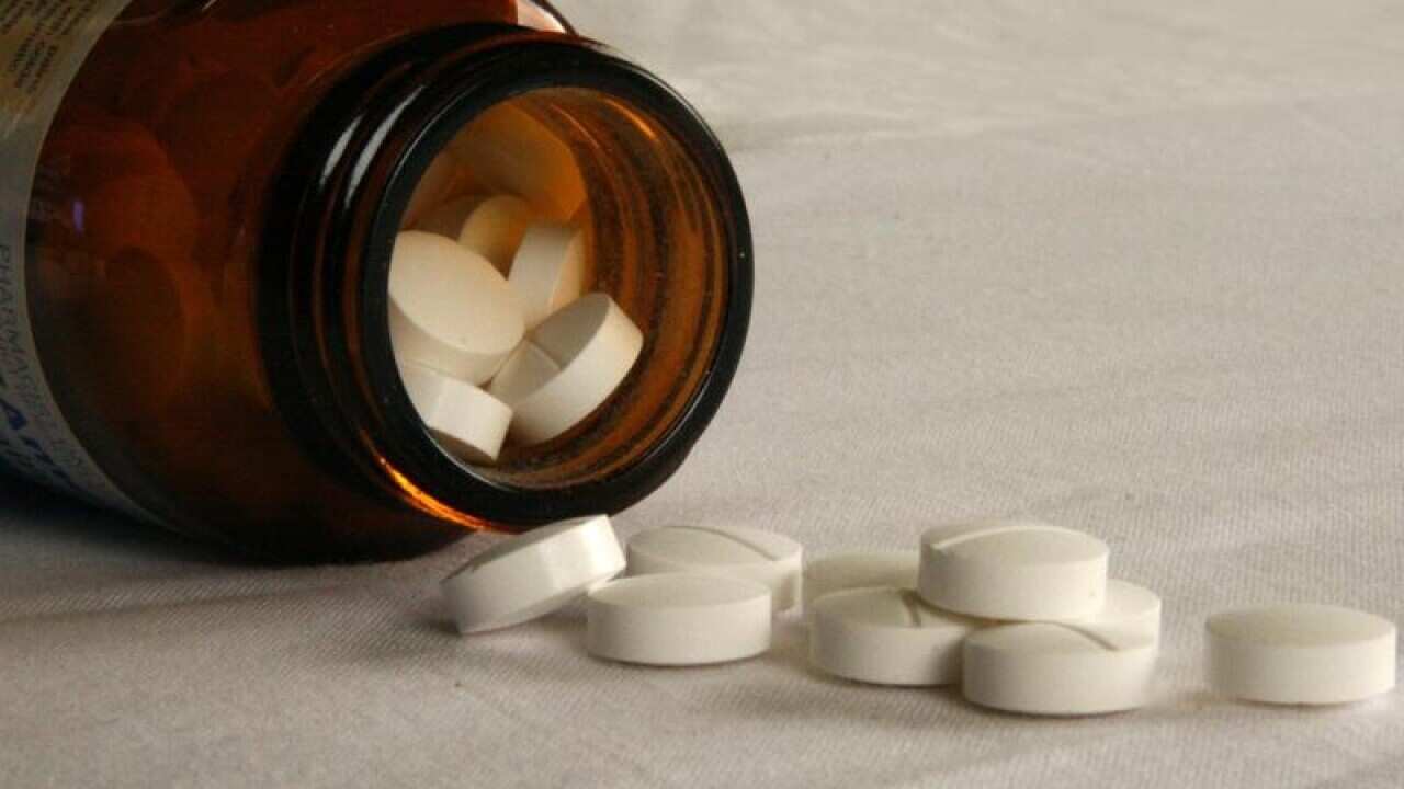 Tablets fall from a jar of medicine