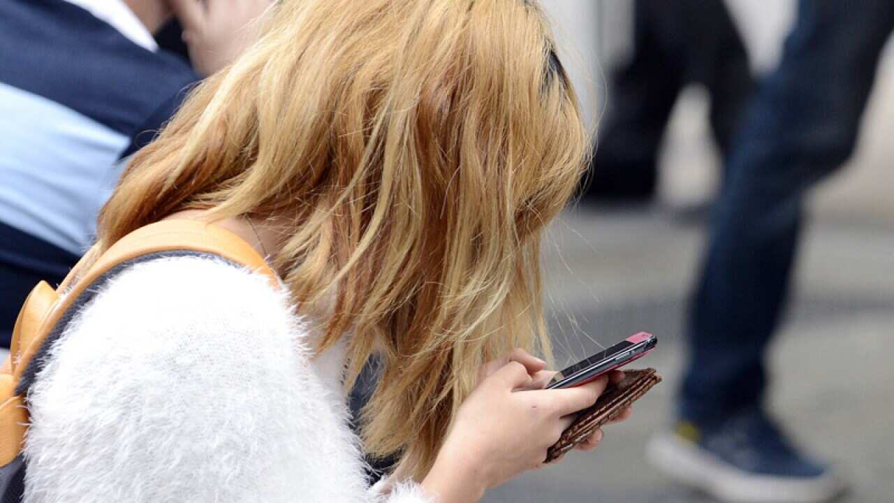 A young woman looks at her mobile phone in Brisbane