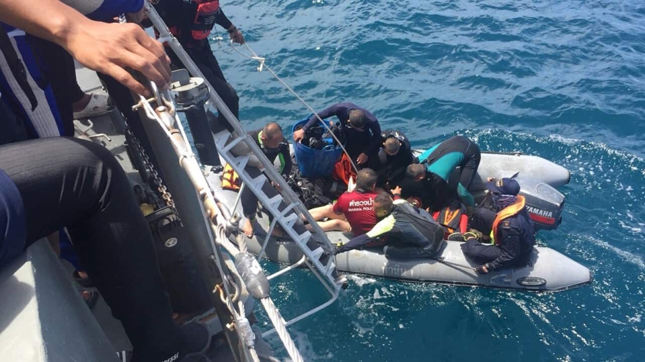 Divers on a rubber raft retrieve a body during a search operation in the water off Phuket, Thailand.