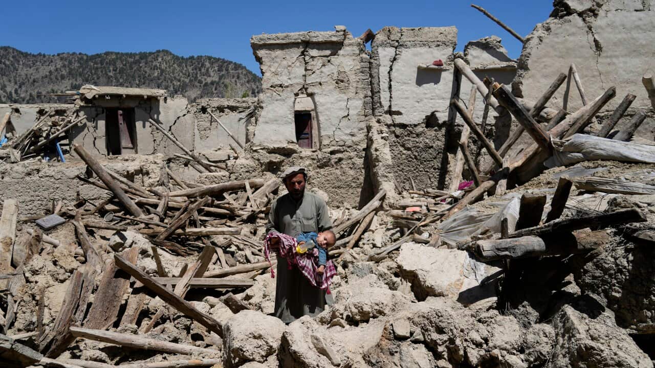 An Afghan man carries his child amid destruction after an earthquake in Gayan village, in Paktika province, Afghanistan. 