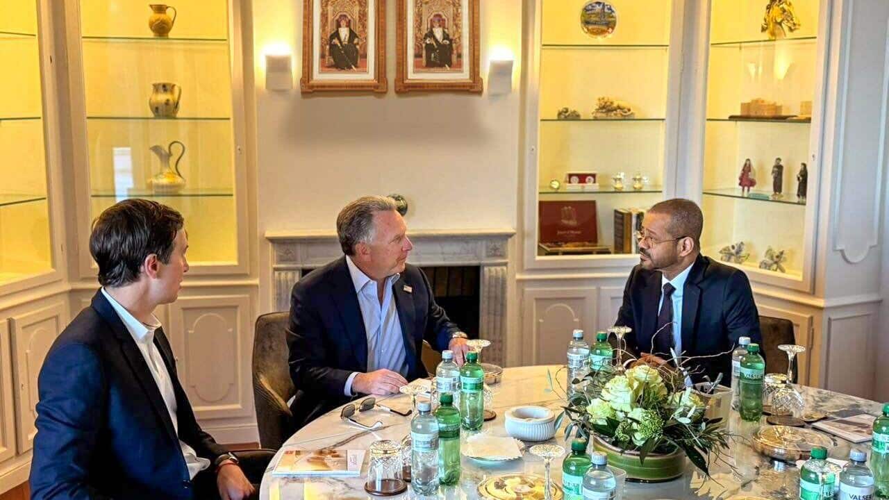Three men sitting at a white marble table.