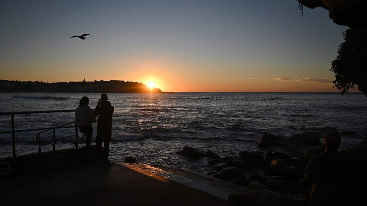 Beachgoers watch the sunrise at Bondi Beach in Sydney