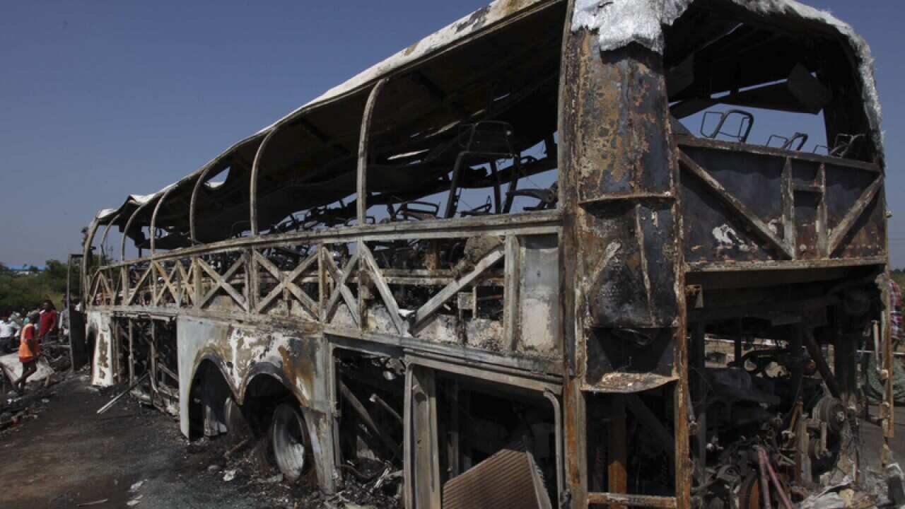Rescuers and others stand near the debris of a bus crash