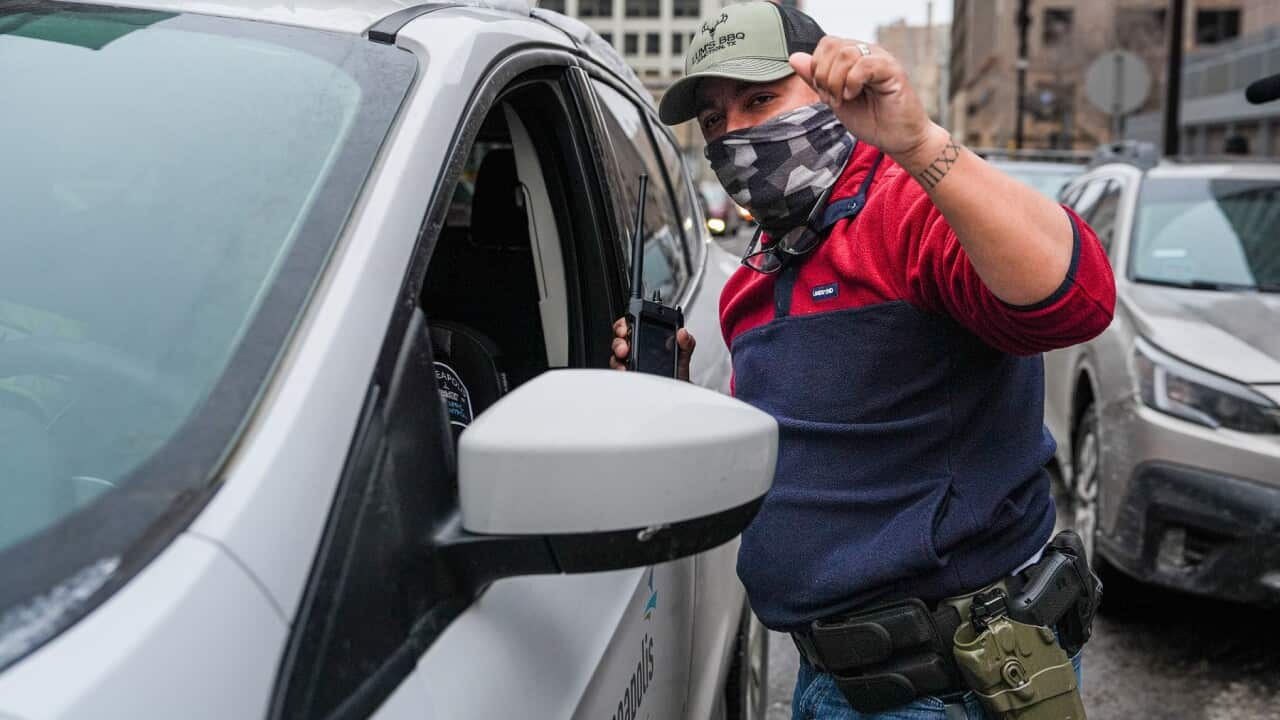 A federal agent of the Immigration and Customs Enforcement talks to a person in a car (AAP)