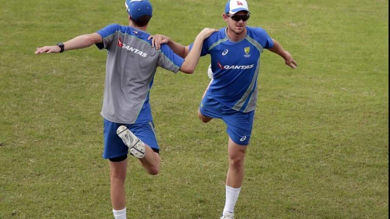 Josh Hazlewood, right, and teammate stretch during a practice session.