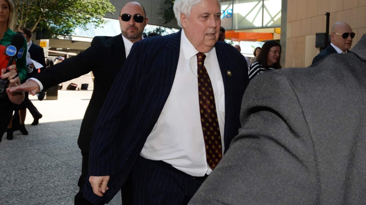 Businessman Clive Palmer, flanked by security guards