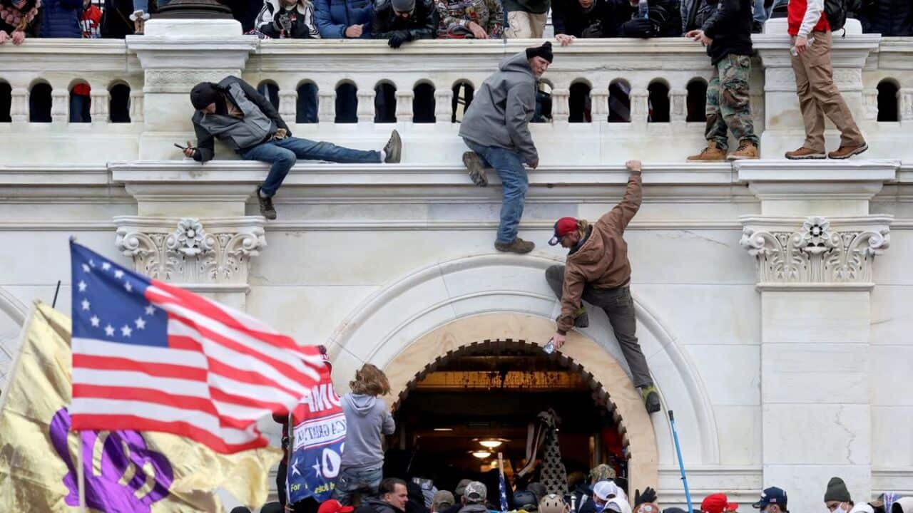 A mob of supporters of US President Donald Trump fight with members of law enforcement as they storm the U.S. Capitol Building in Washington DC.