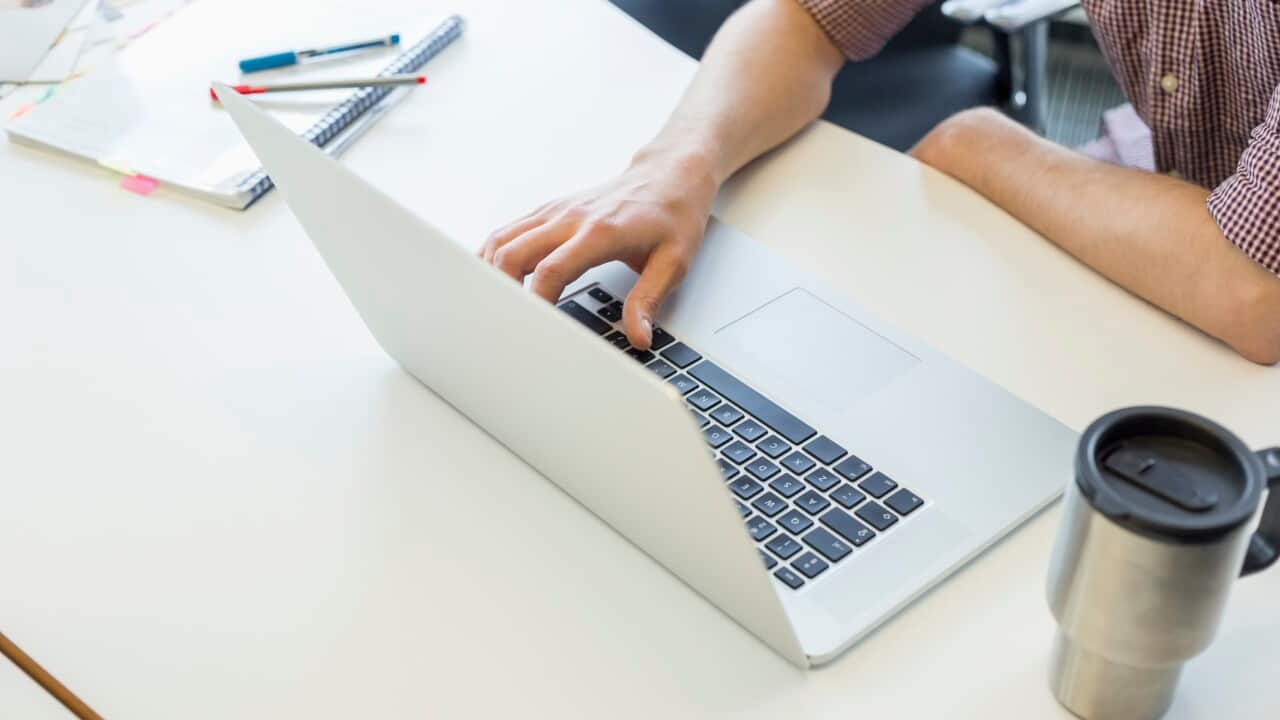 Cropped image of man using laptop at desk in creative office