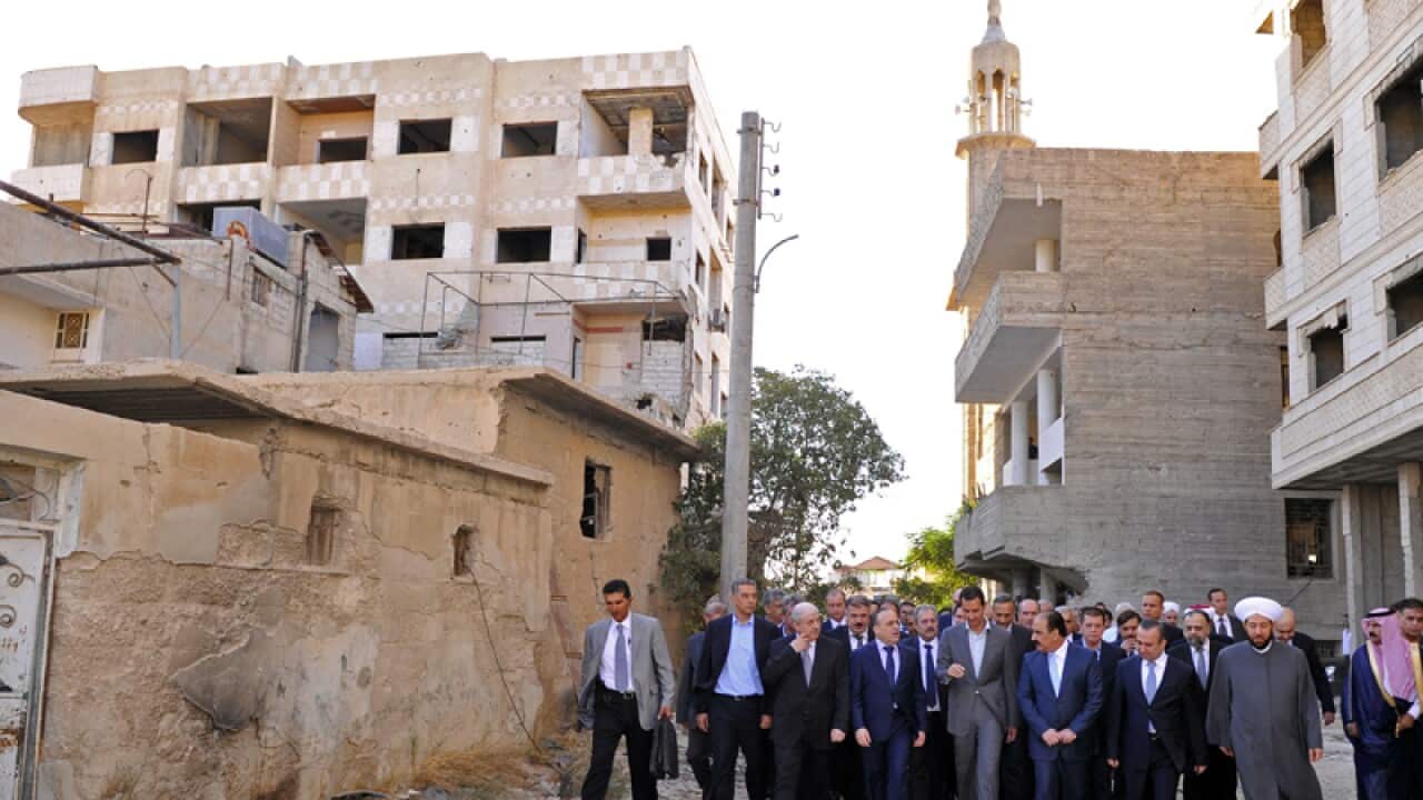 Syrian President Bashar Assad, center, walks on a street