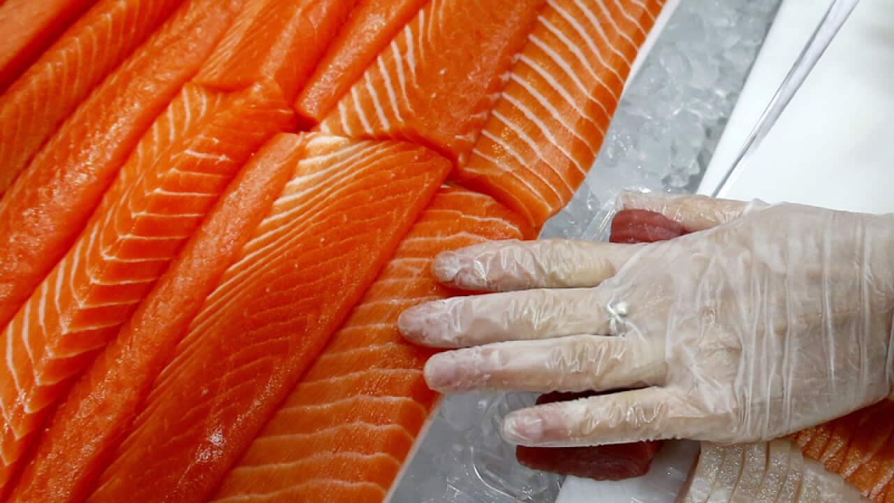 A woman cuts salmon at the Sydney Fish Markets
