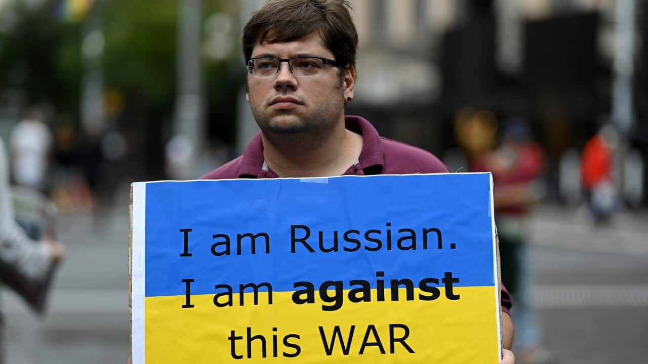 Protestors hold placards during a rally against the war in Ukraine at Sydney Town Hall in Sydney, Sunday, March 6, 2022.