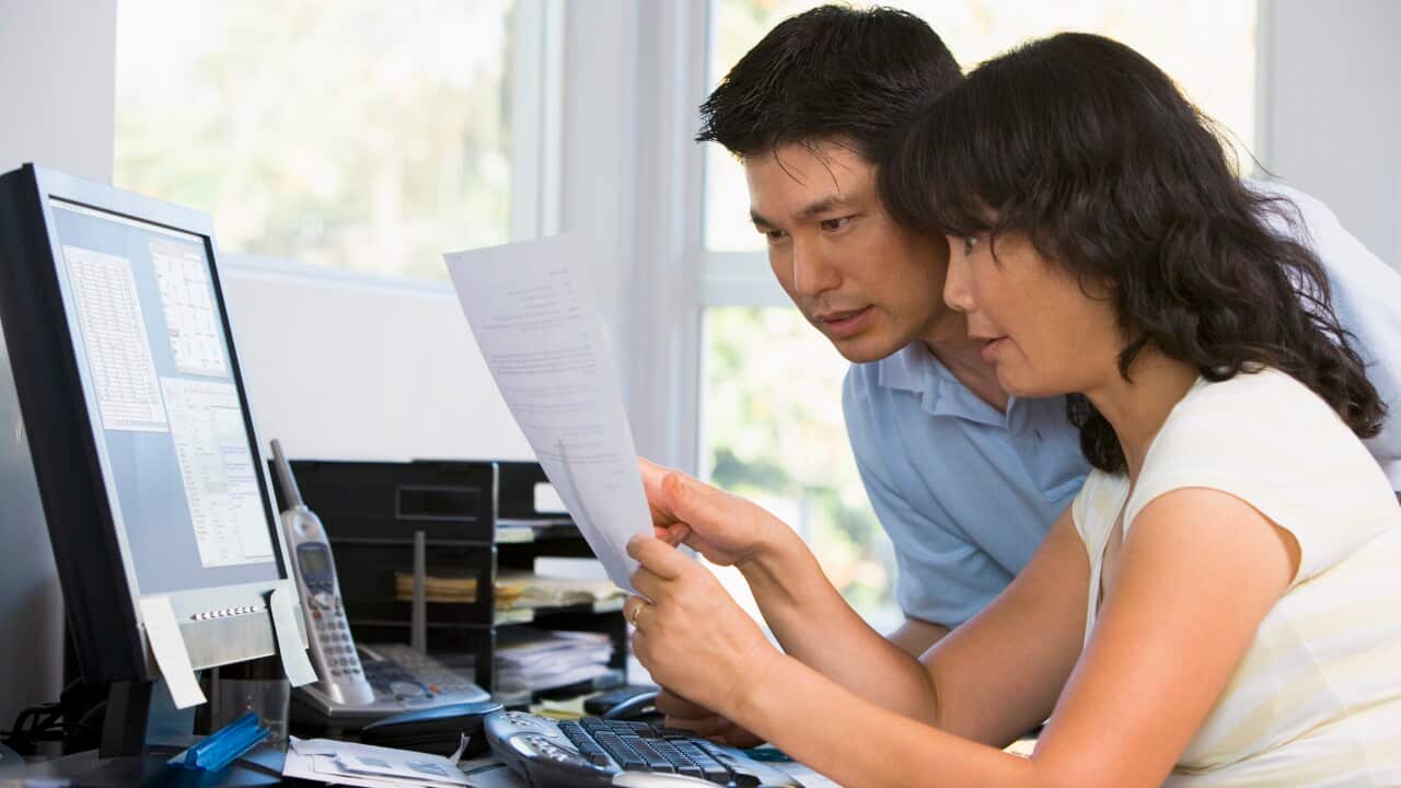 Couple in home office with computer and paperwork pointing