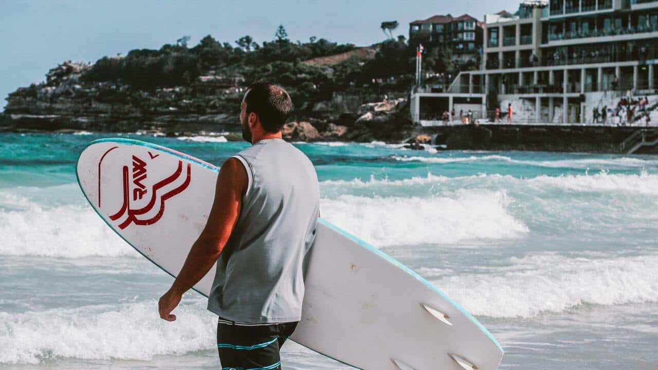 A representative of a man going surfing at a beach in Sydney.