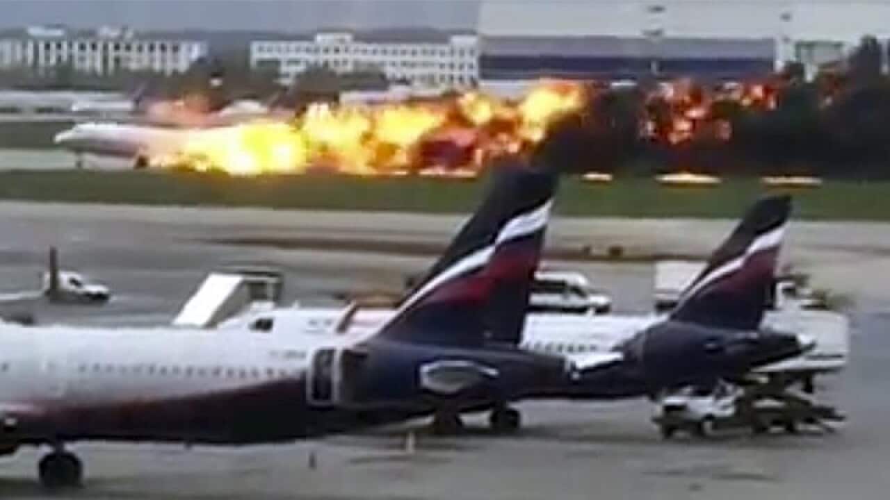 The plane on the Moscow runway with the fire burning at the back