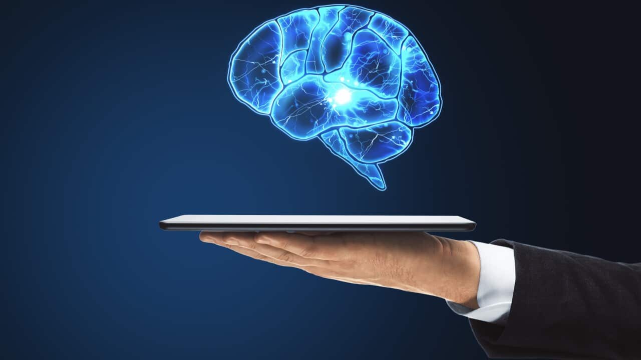 Hand holding tablet with glowing brain