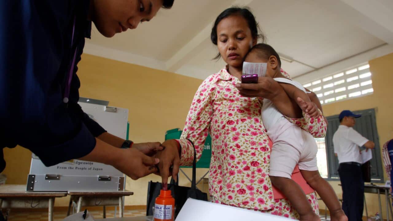 Local has her finger in an ink bottle after voting at a polling station in Phnom Penh, Cambodia