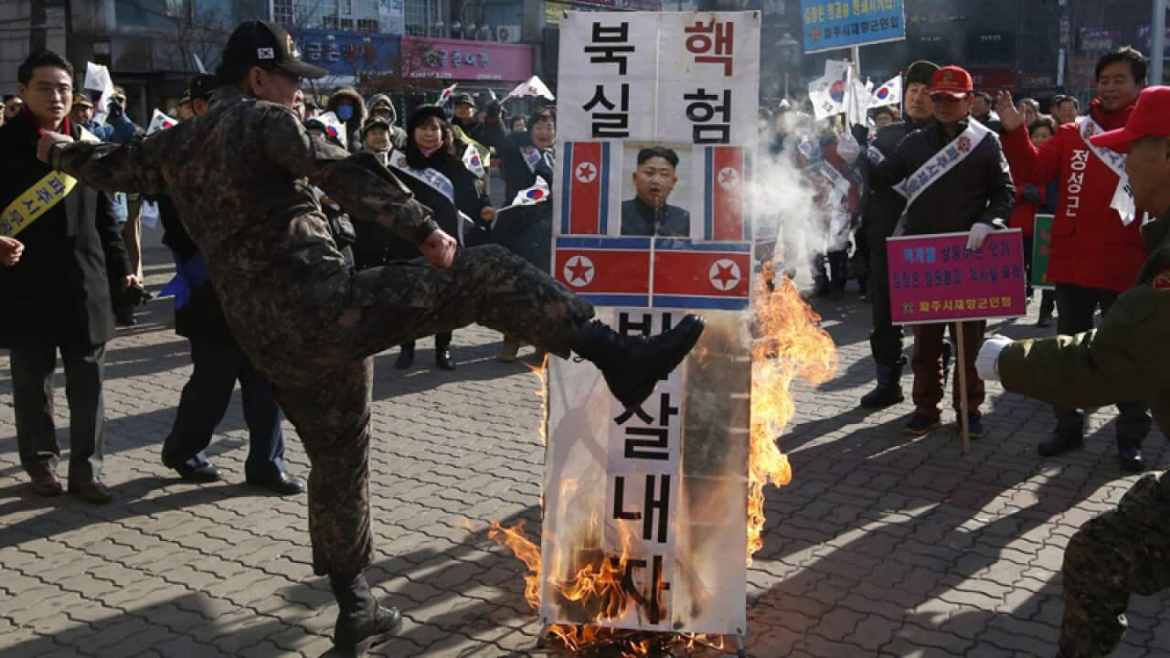 A member of a South Korean conservative group kicks a burning banner