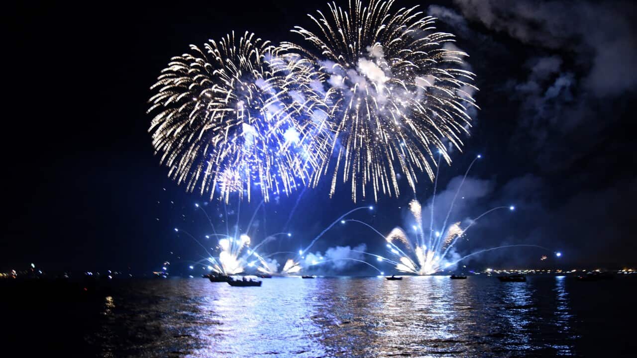 Blue fireworks explode above a harbour