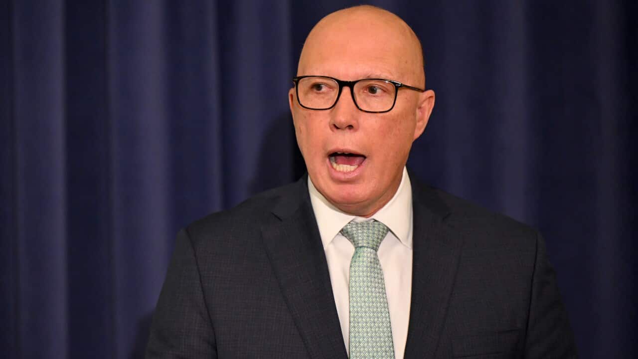 Peter Dutton, wearing a suit, tie, and glasses, speaks.