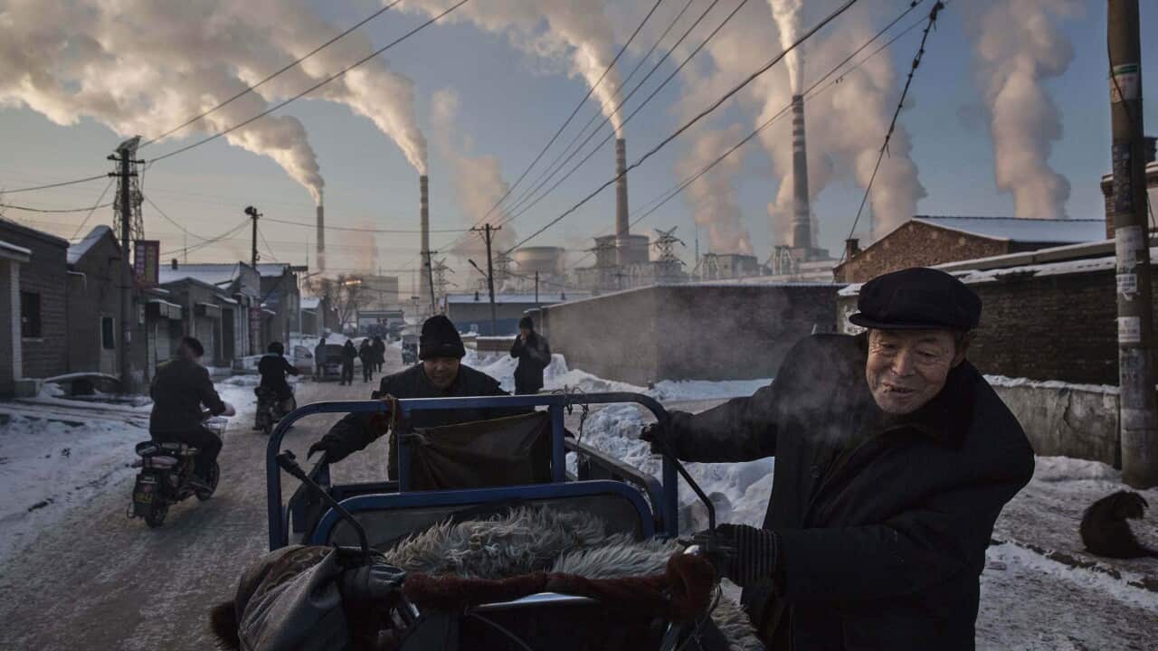 Chinese men pulling a tricycle in a neighborhood next to a coal-fired power plant in Shanxi, China, on Nov. 26, 2015. 