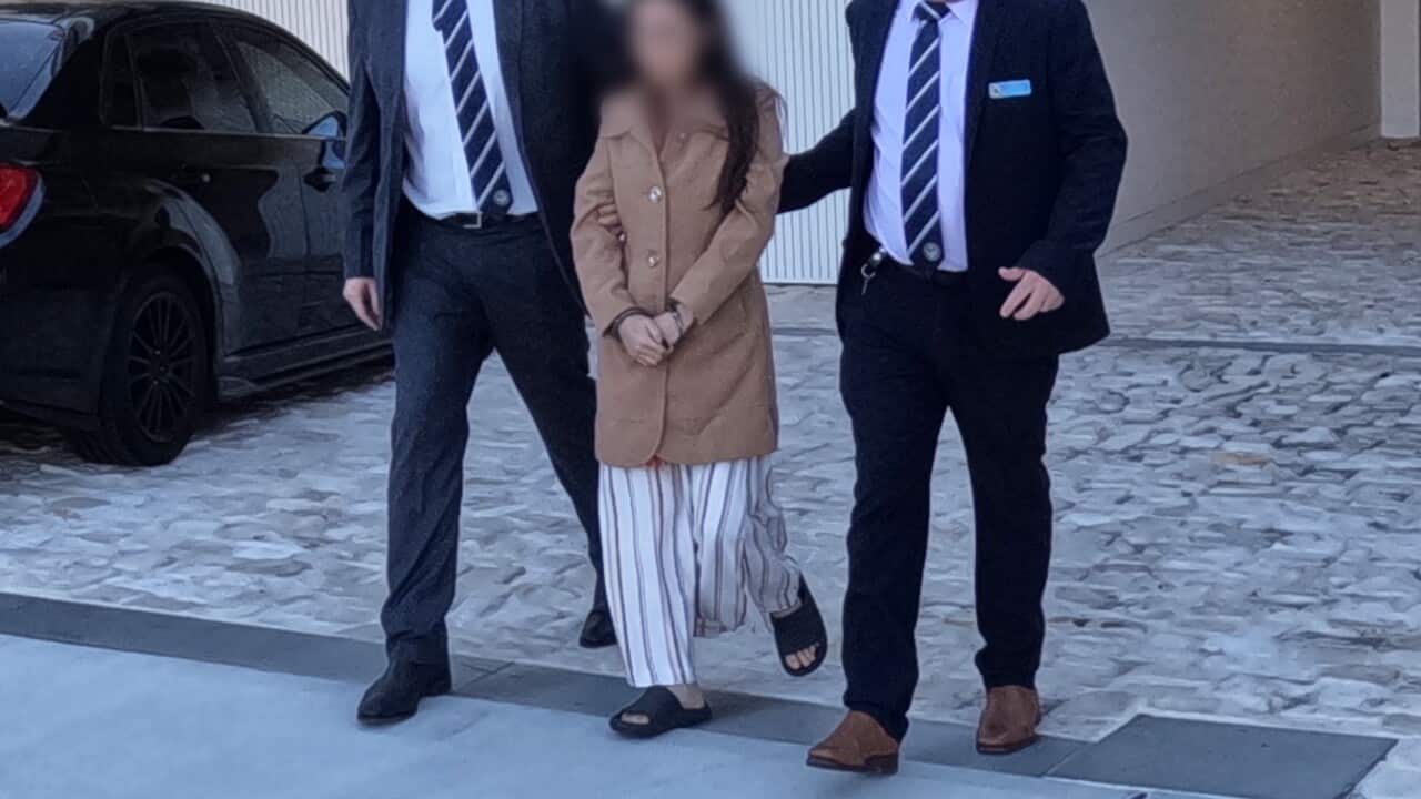 Two police officers escorting a woman from a property.