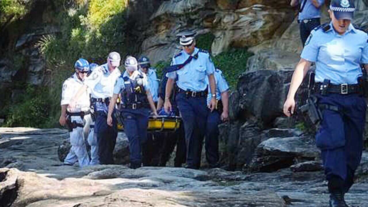 Police carry a body of a man who slipped and fell off a cliff, Sydney