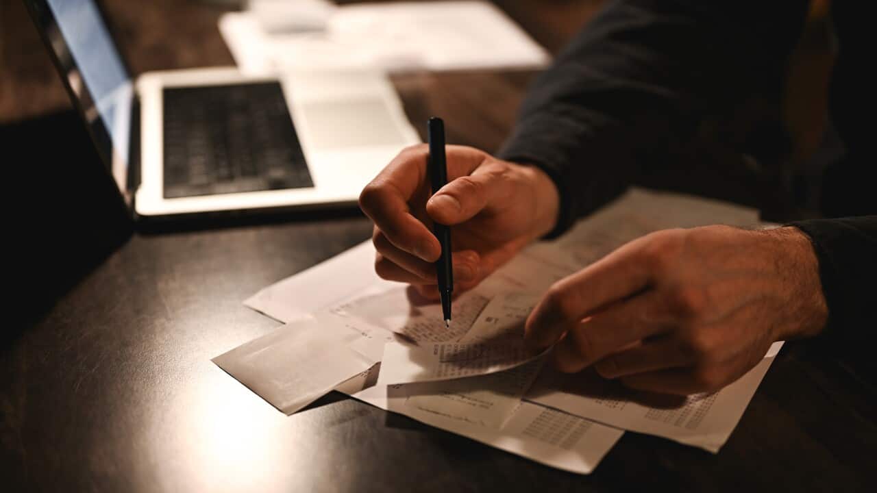 Hands reviewing paperwork and receipts beside a laptop on a desk