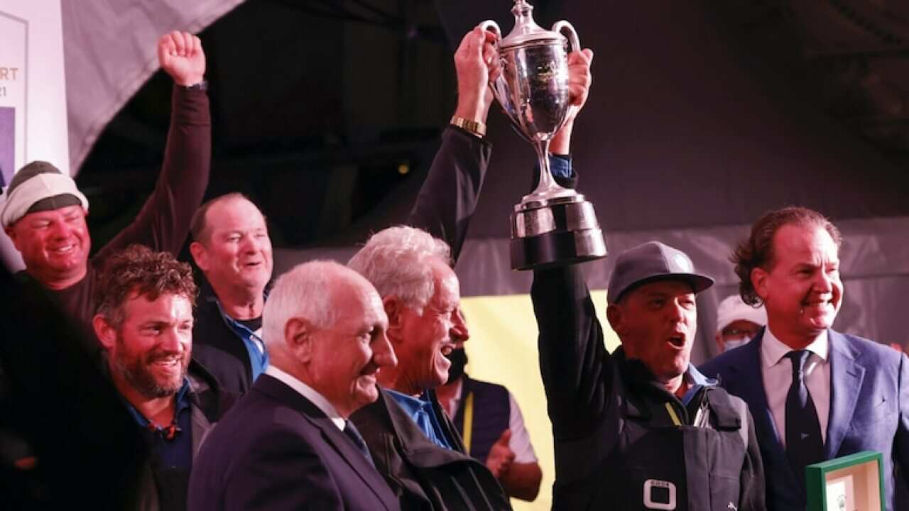 Peter Harburg, owner of line honours winner BlackJack (centre) and Skipper Mark Bradford (second right) receive the trophy