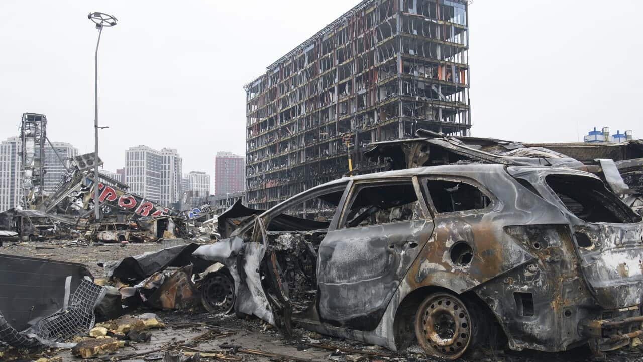 A burnt-out car in front of a destroyed building in Ukraine