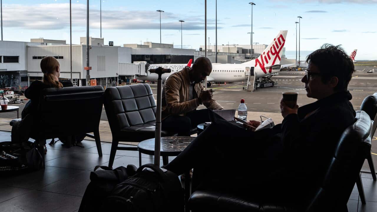 Passengers sitting on seats while waiting for their flights at Sydney Airport.