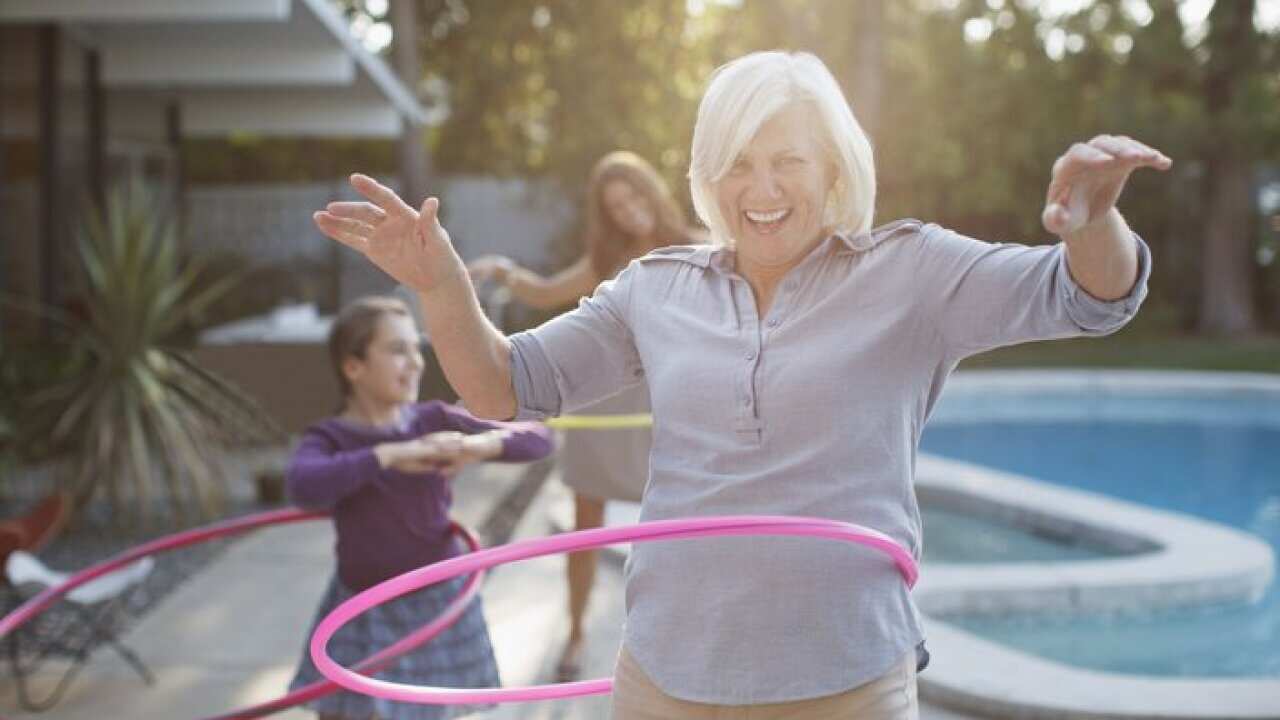 Older woman hula hooping in backyard