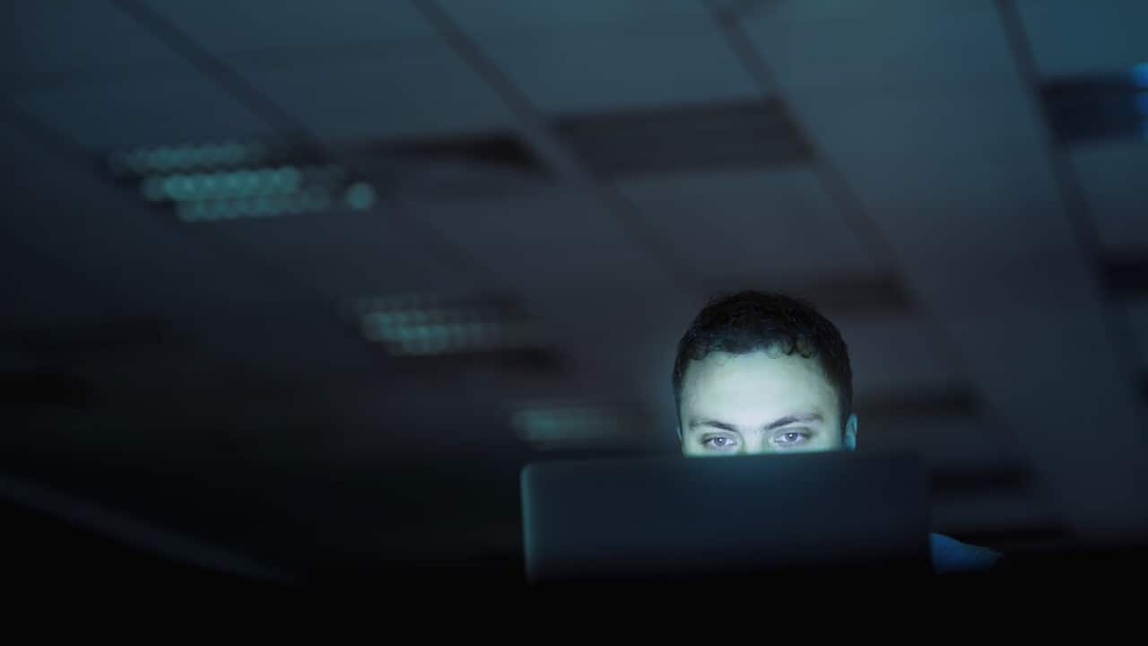 Man looking at laptop computer in office at night