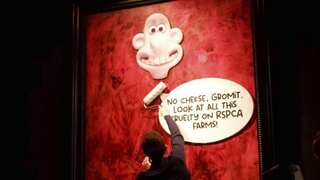 An activist pastes a picture of Wallace, from the 'Wallace and Gromit' comedy series, over a portrait of Britain's King Charles III.