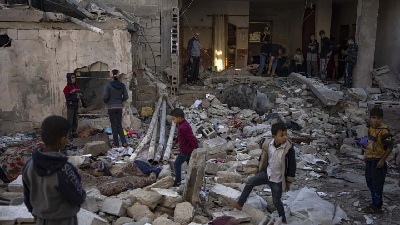 Children stand in a pile of rubble
