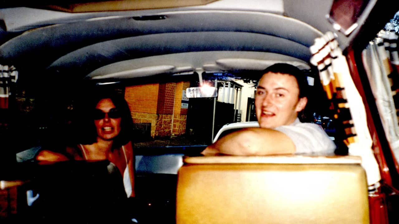 A woman and man smiling while sitting in a camper van.