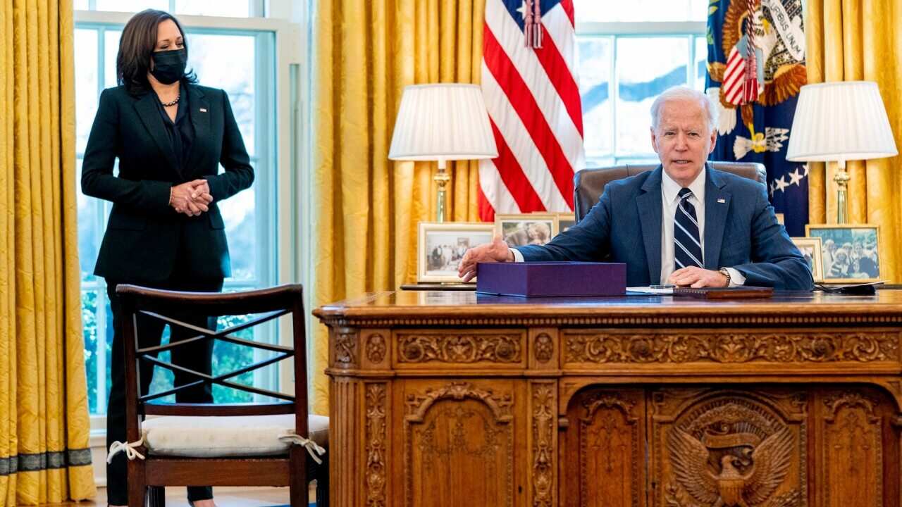 President Joe Biden, accompanied by Vice President Kamala Harris, looks up after signing the American Rescue Plan