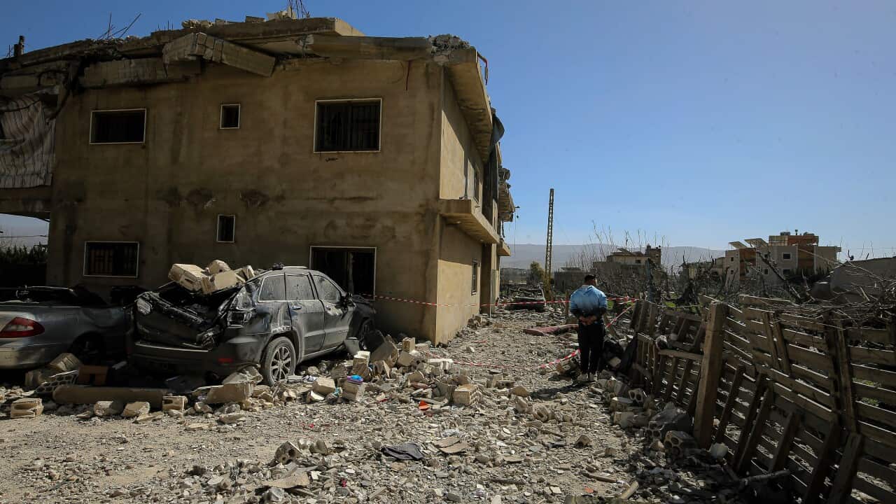 A man standing near a building that has been badly damaged.