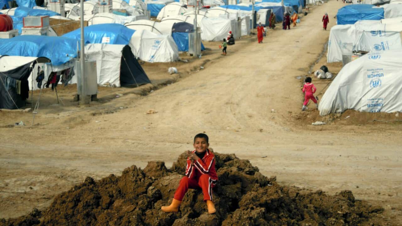 a Syrian Kurdish refugee plays on a pile of dirt in the Dumiz refugee camp in northern Iraq.