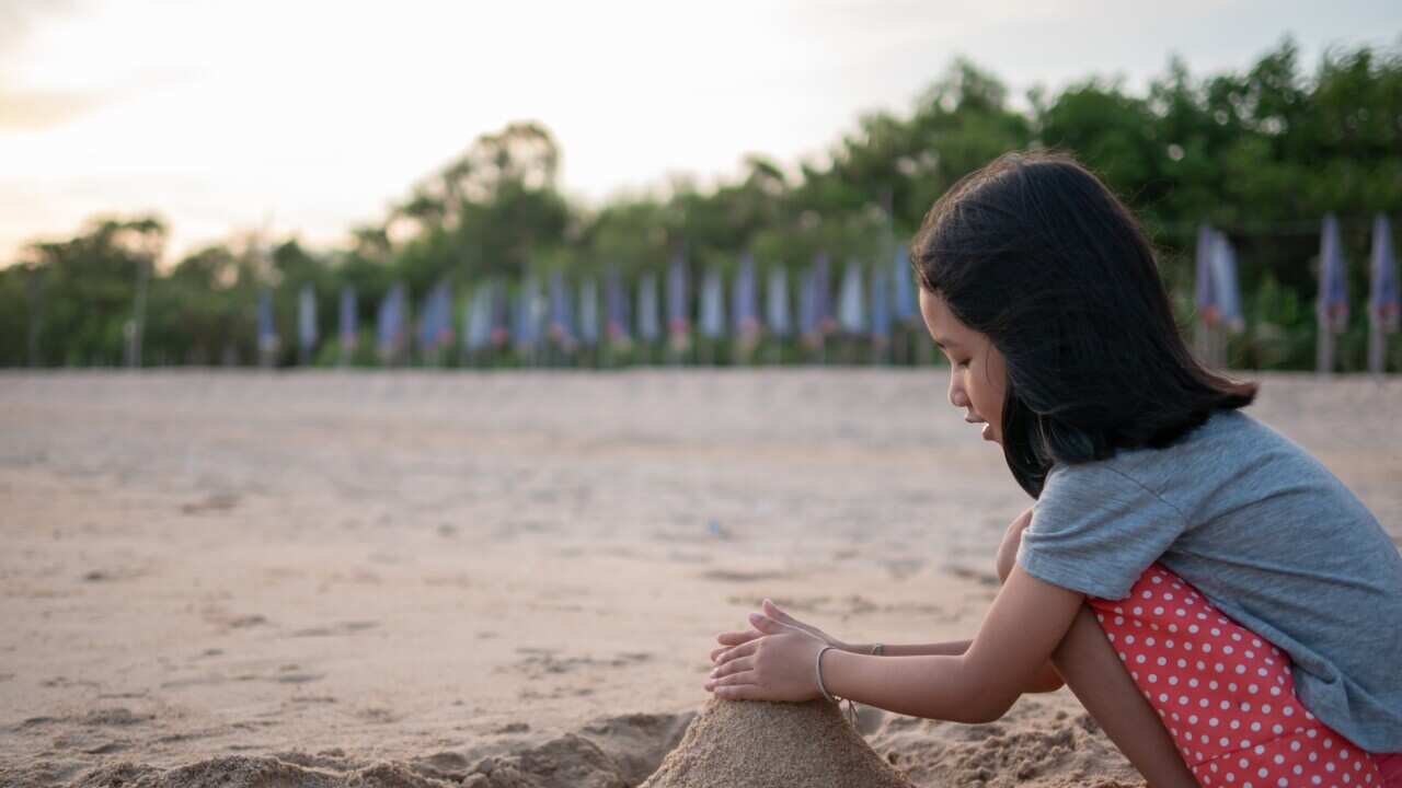 Side View Of Woman Sitting On Beach