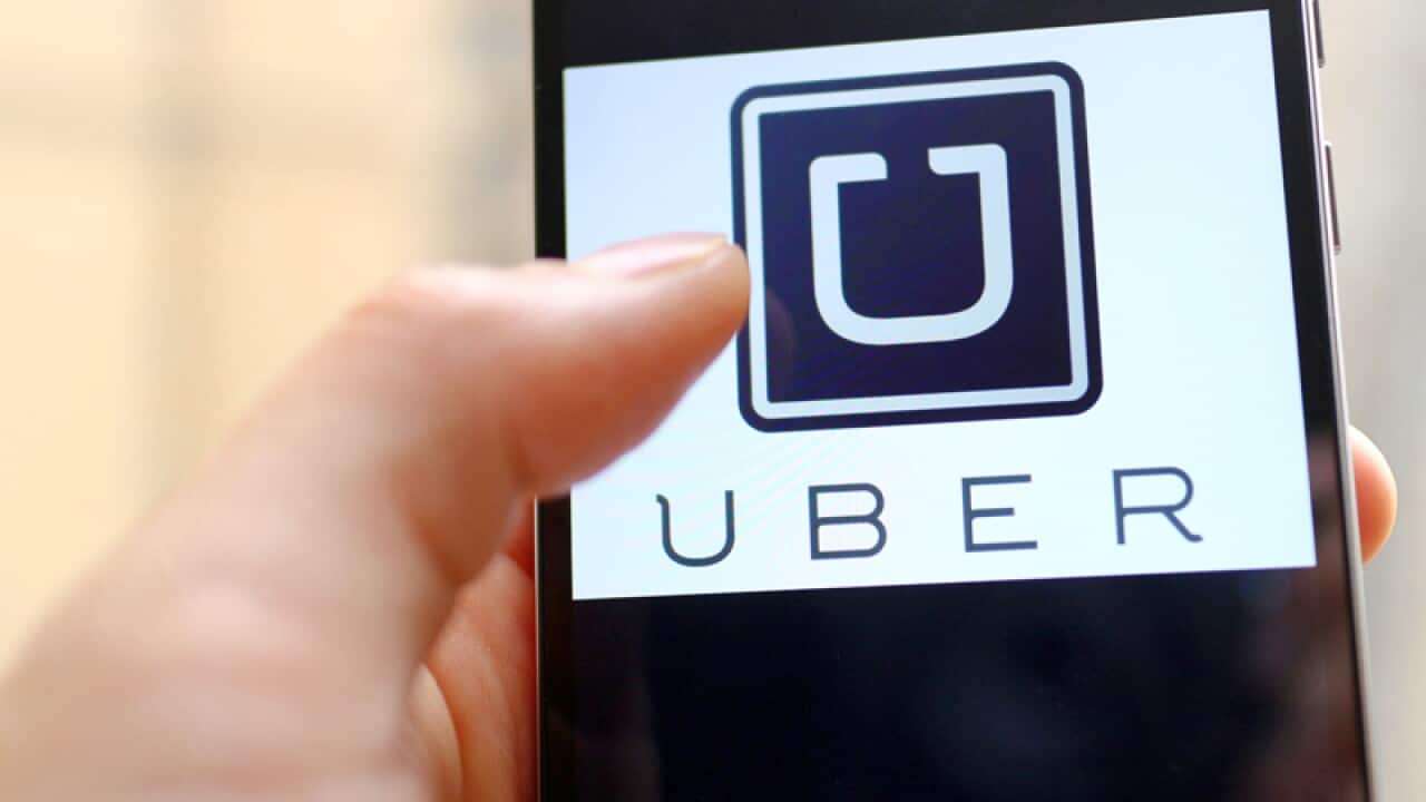A mobile phone user shows the logo of car-hailing app Uber