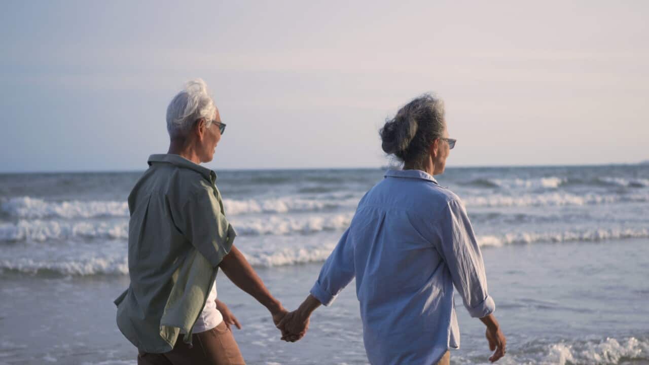 happy-asian-senior-man-and-woman-couple-holding-hands-walking-on-the-beach-with-sunset-SBI-351627589.jpg