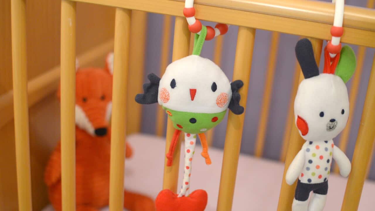 A child's soft toys hang on the side of a cot