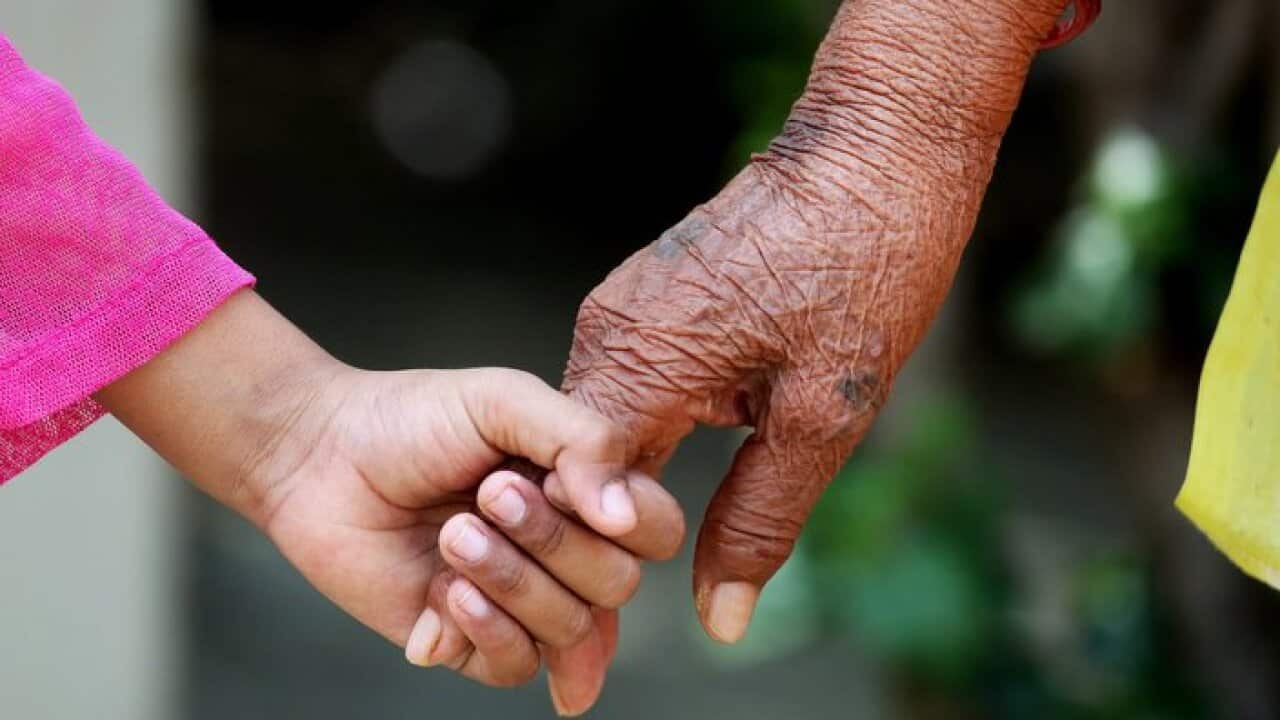 A young girl holds the hand of an elderly resident
