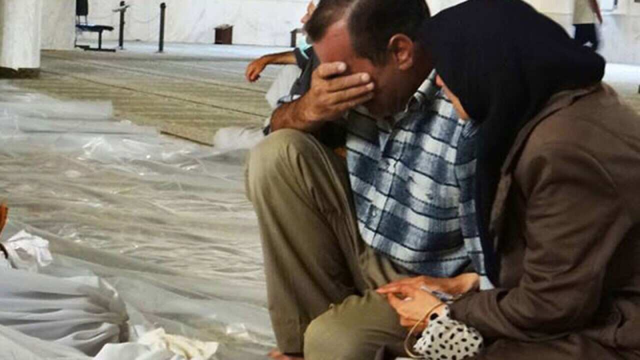 A man and woman mourn over the dead bodies of Syrian men