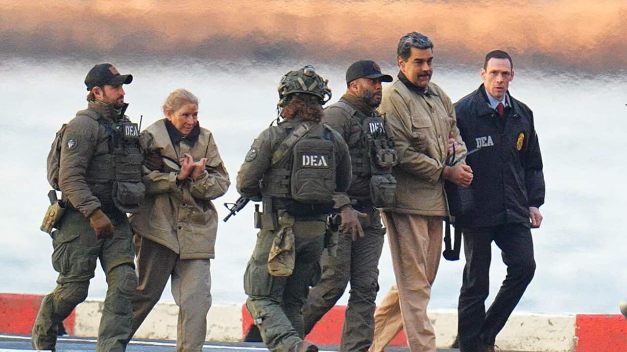 Nicolas Maduro and Cilia flores being transported by men in uniforms that say DEA.