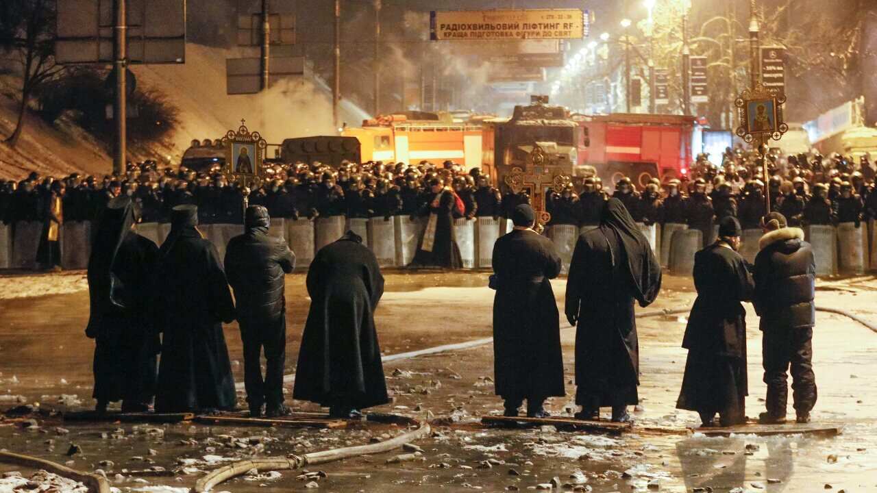Ukrainian priests stand in line between protesters and riot police during an anti-government protest in Kiev - AAP-1.jpg