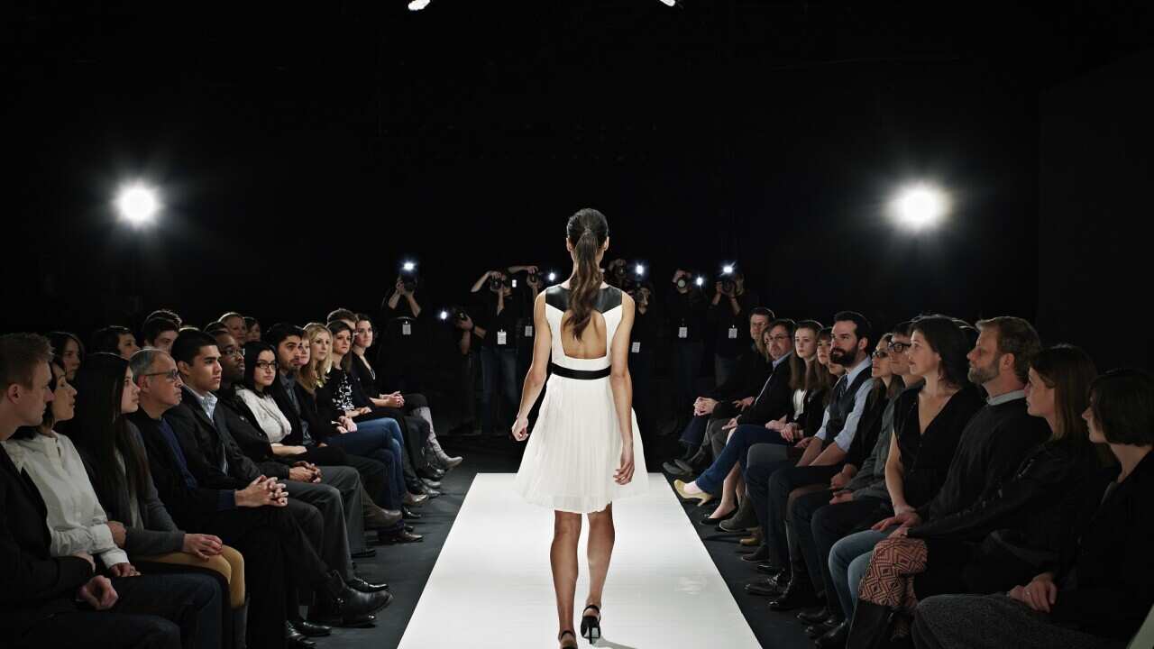 Model walking down catwalk during fashion show