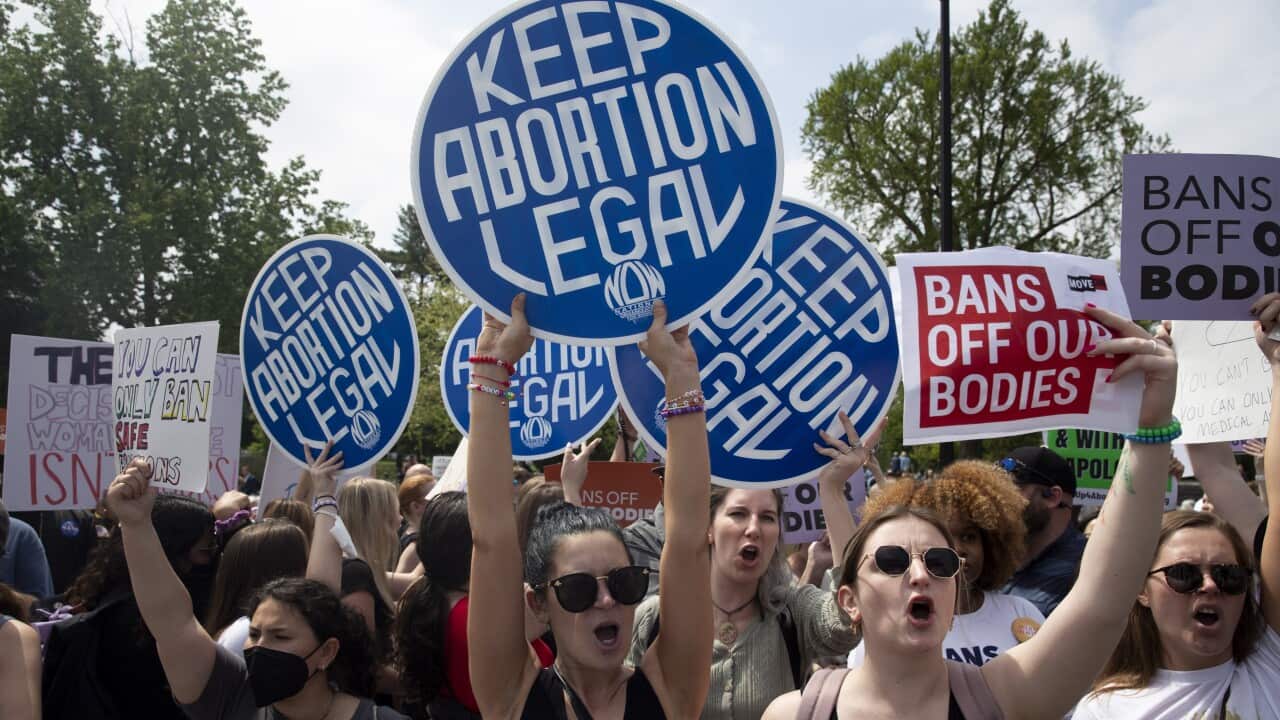 Women gather and chant with signs up that say "Keep abortion legal".